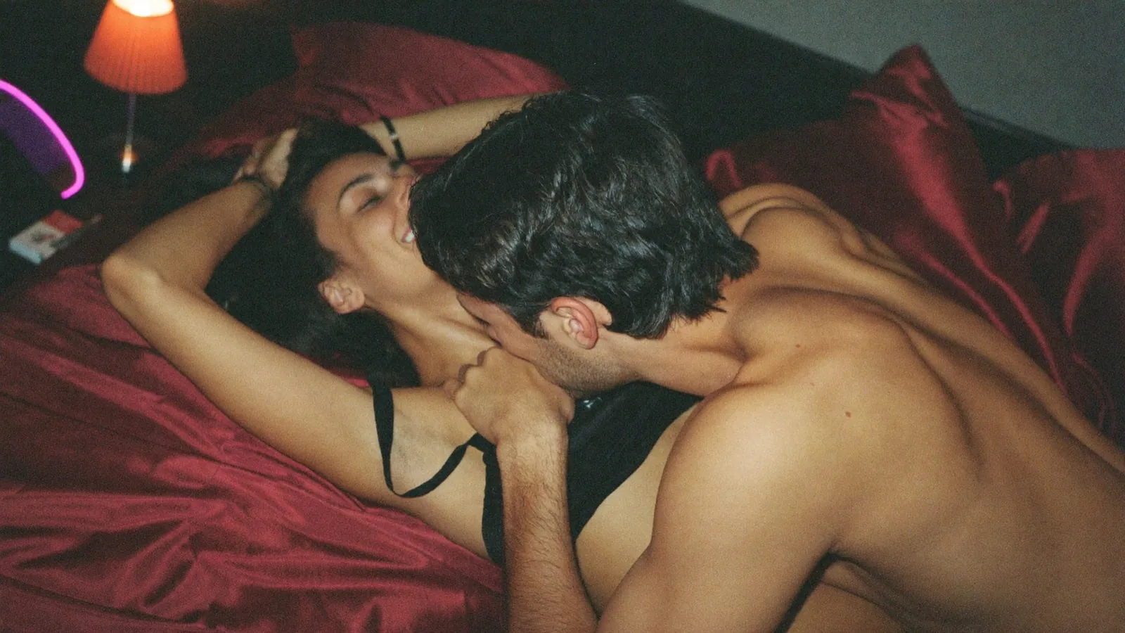 Couple kissing on red satin sheets