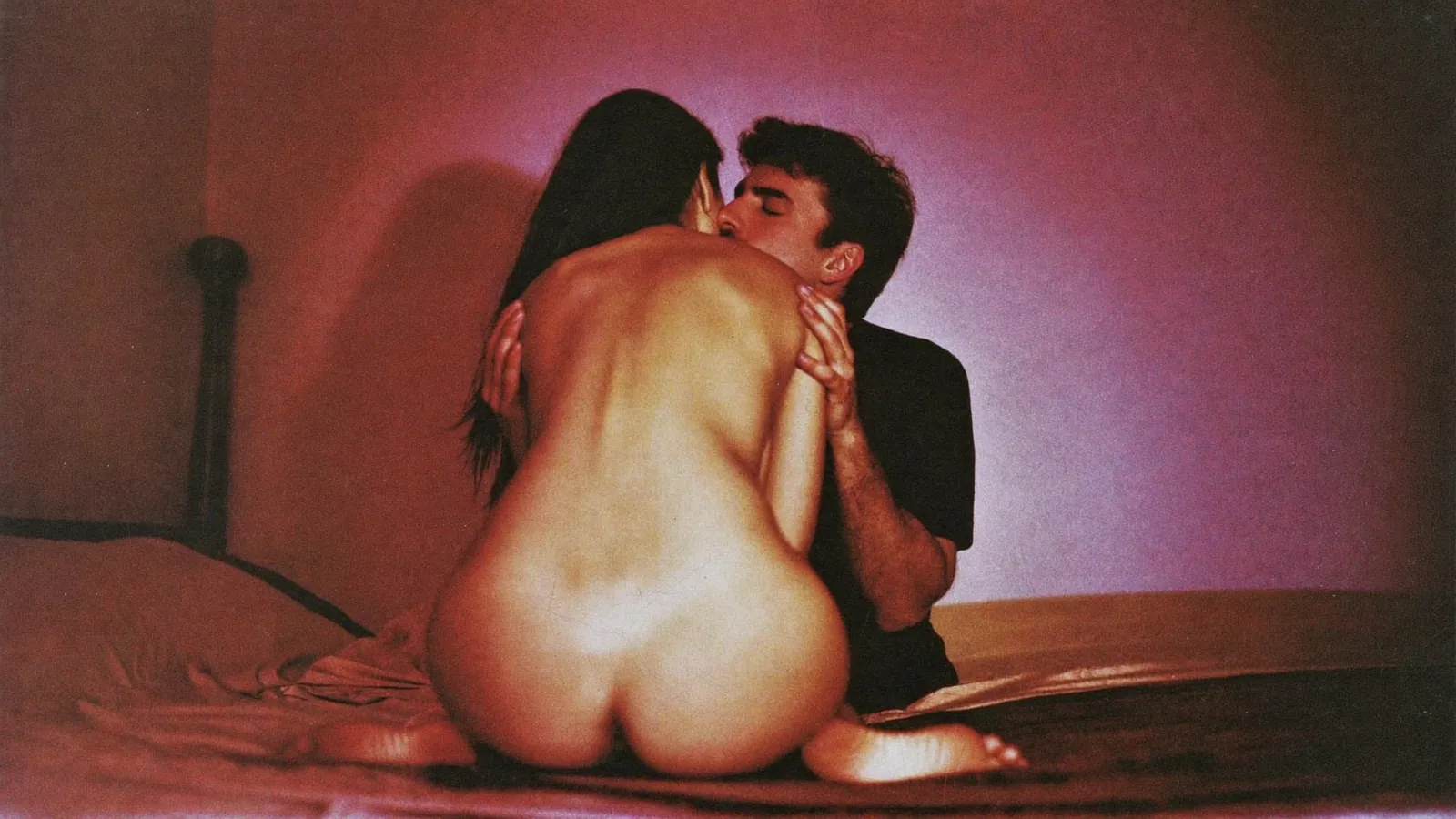 Couple kissing on a bed in violet light